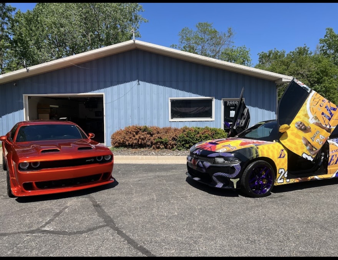 Two custom Dodge muscle cars parked outside the House of Motion detailing shop in Holt, Michigan